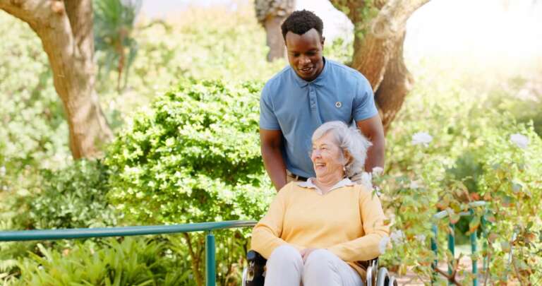 assisted living resident with caregiver walking in the garden